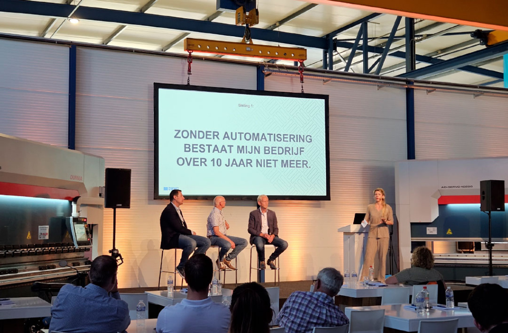 V.l.n.r. Corné van Opdorp, Guido Wensink en Koos Schep discussiëren onder leiding van dagvoorzitter Marelle van Beerschoten over automatisering en het metaalbedrijf van de toekomst.
