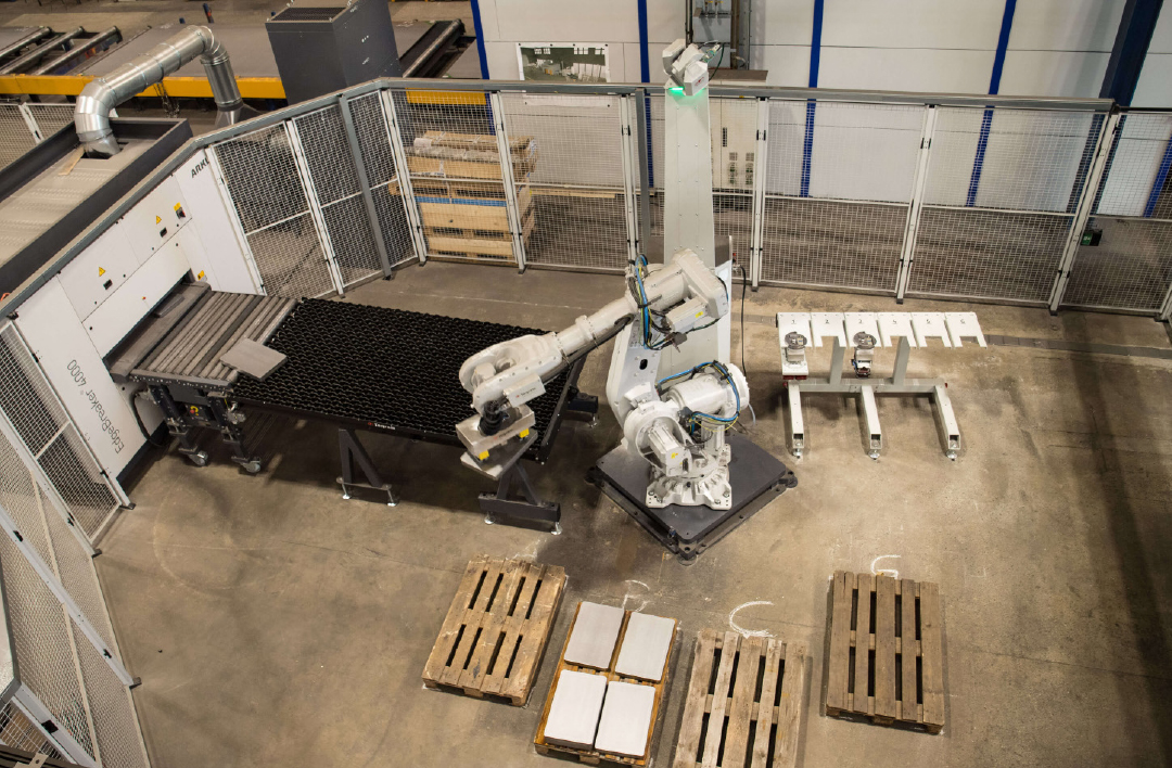 Een tweede robot aan het einde van de ontbraamlijn stapelt de afgewerkte onderdelen automatisch op pallets voor verder transport binnen de fabriek.